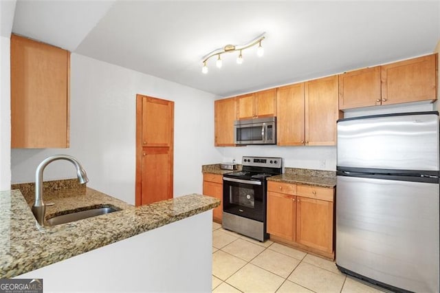 kitchen featuring sink, stone countertops, light tile patterned floors, kitchen peninsula, and stainless steel appliances