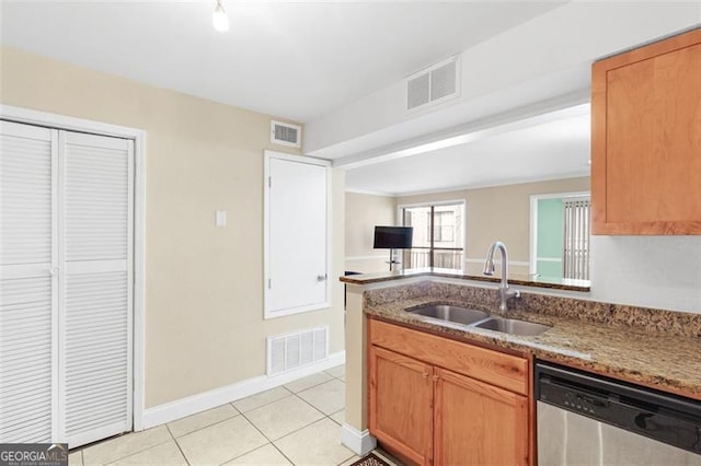 kitchen with light tile patterned flooring, stainless steel dishwasher, sink, and stone counters