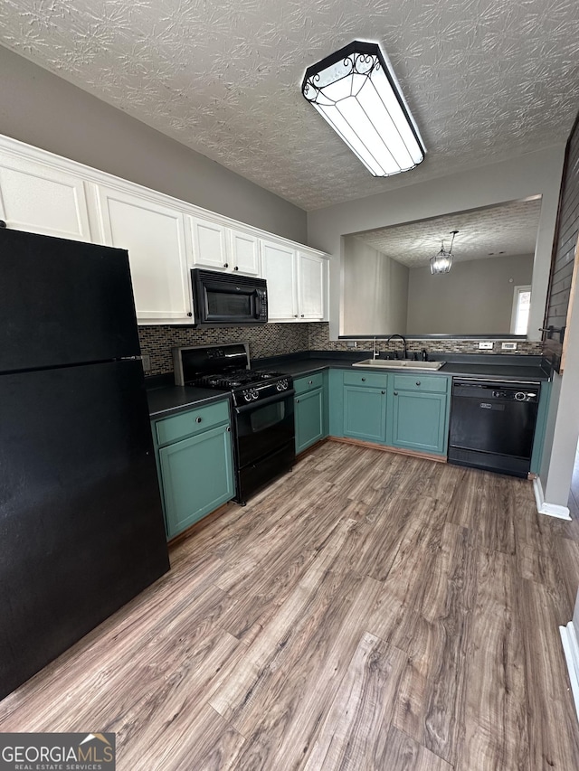 kitchen featuring sink, tasteful backsplash, black appliances, a textured ceiling, and light wood-type flooring