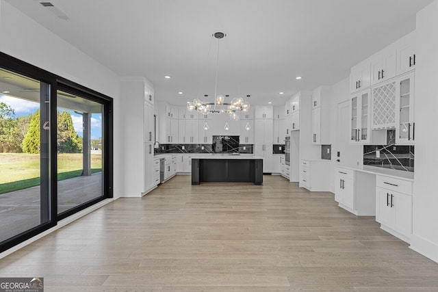 kitchen with white cabinetry, a center island, light wood-type flooring, and pendant lighting