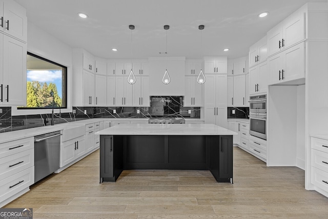 kitchen featuring white cabinetry, appliances with stainless steel finishes, a center island, and light stone countertops