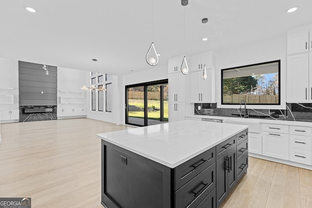 kitchen with pendant lighting, white cabinetry, backsplash, light hardwood / wood-style floors, and a kitchen island