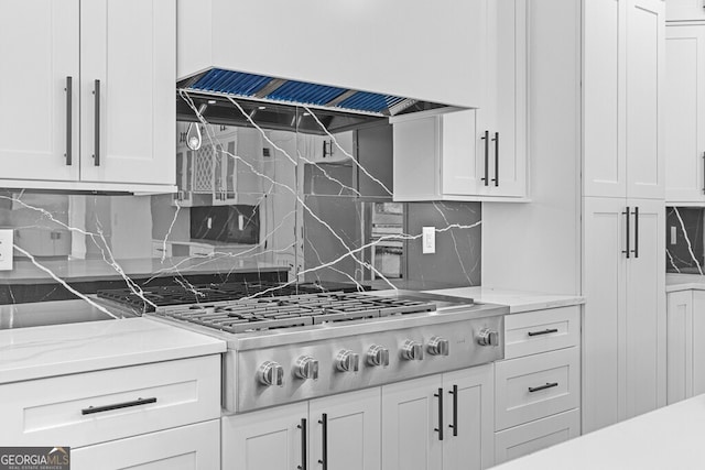 kitchen with white cabinets, decorative backsplash, custom exhaust hood, stainless steel gas cooktop, and light stone countertops