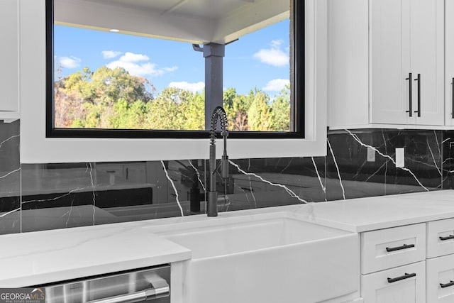 kitchen with white cabinetry, sink, tasteful backsplash, and light stone countertops