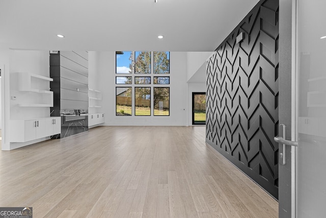 unfurnished living room with a high ceiling and light hardwood / wood-style floors