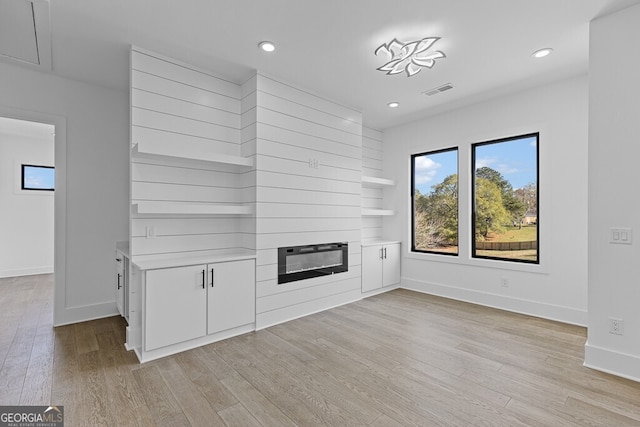 unfurnished living room with light hardwood / wood-style floors and a large fireplace