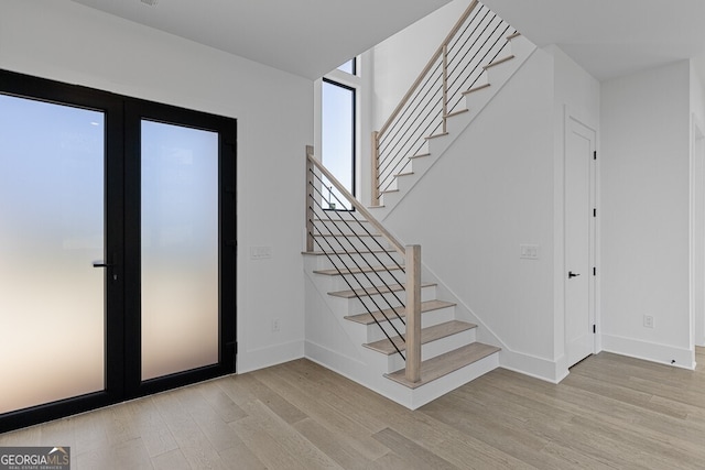 stairs featuring french doors and wood-type flooring