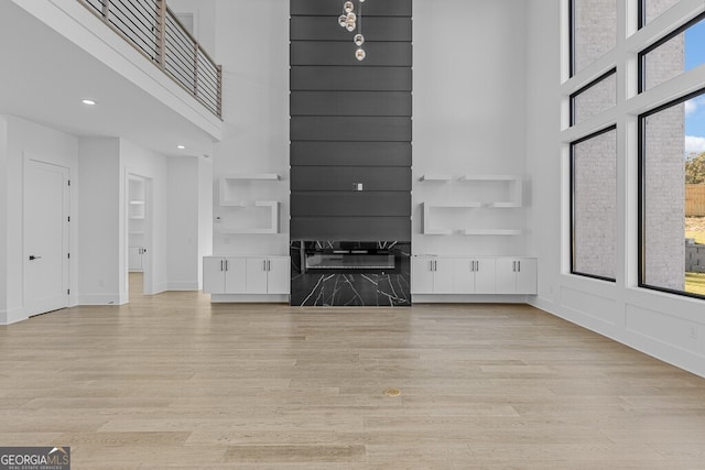 unfurnished living room featuring light hardwood / wood-style floors and a high ceiling