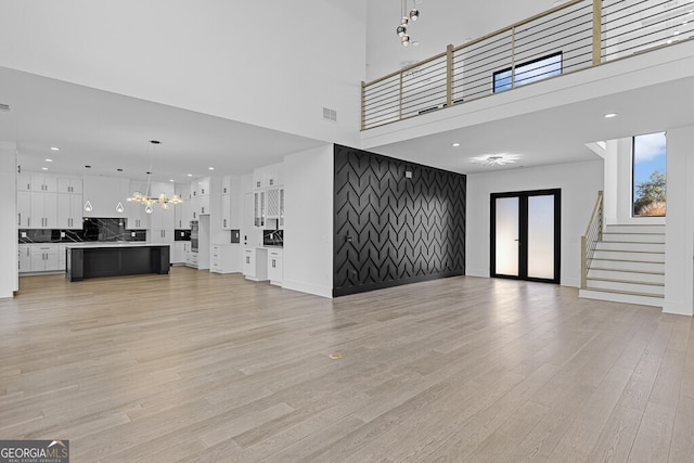 unfurnished living room with a chandelier and light hardwood / wood-style floors