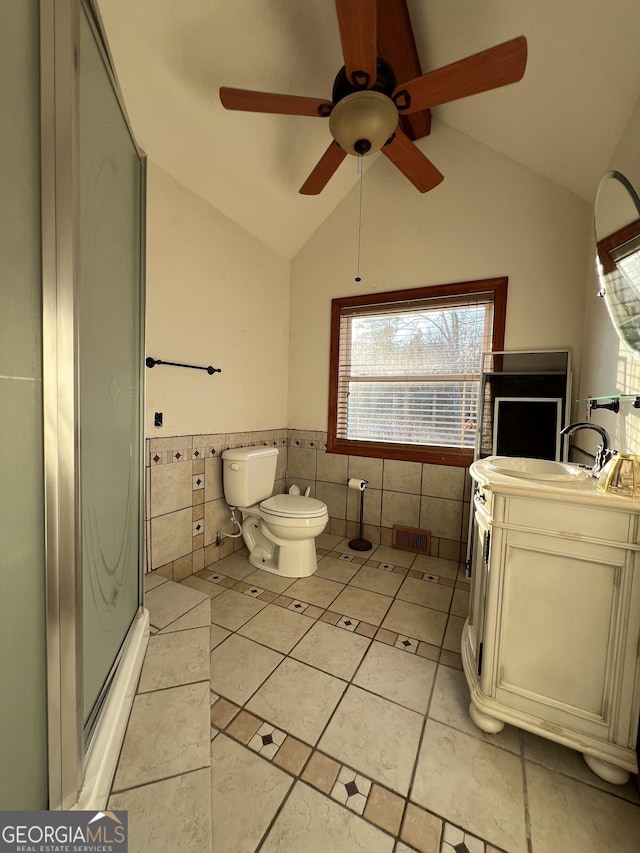 bathroom featuring lofted ceiling, vanity, a shower with shower door, and tile walls