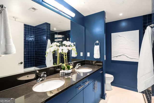 bathroom featuring vanity, tile patterned floors, toilet, and a tile shower