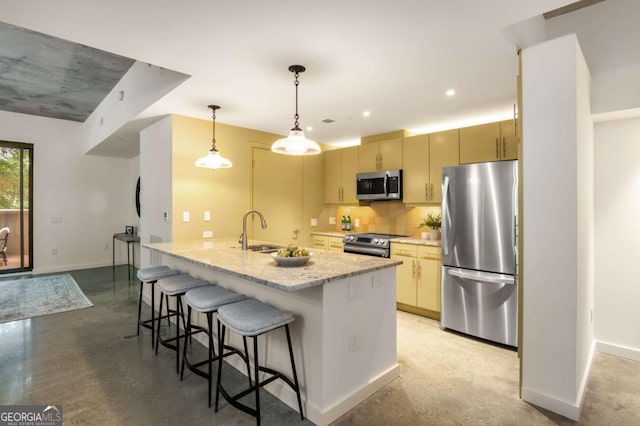 kitchen with sink, light stone counters, tasteful backsplash, decorative light fixtures, and appliances with stainless steel finishes