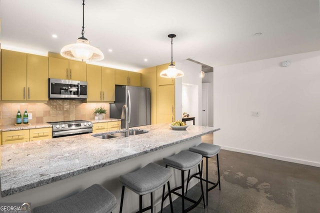 kitchen featuring light stone counters, hanging light fixtures, decorative backsplash, and stainless steel appliances