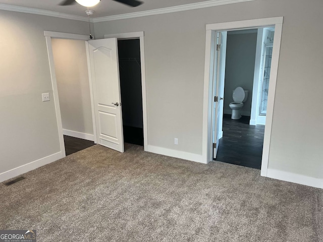 unfurnished bedroom with dark colored carpet, ornamental molding, ensuite bathroom, and a closet