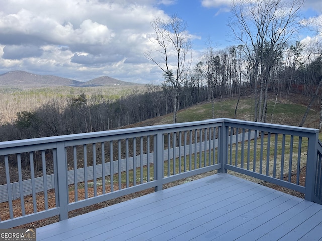 wooden terrace featuring a mountain view and a lawn