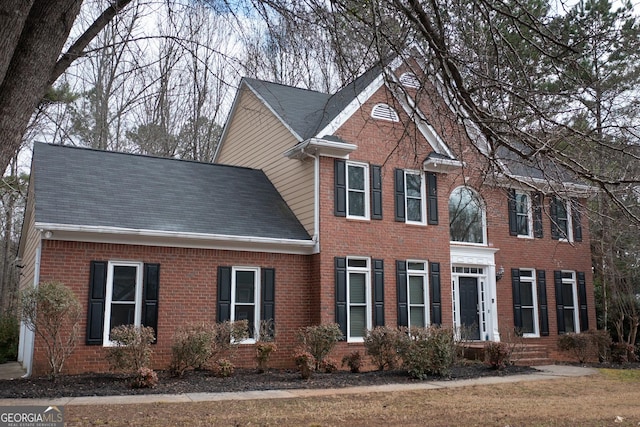 view of front of house with brick siding and roof with shingles