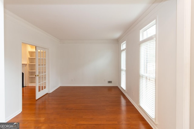 spare room with wood finished floors, visible vents, baseboards, ornamental molding, and french doors