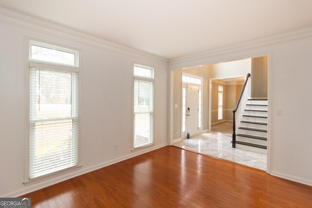 spare room featuring an inviting chandelier, hardwood / wood-style flooring, and ornamental molding