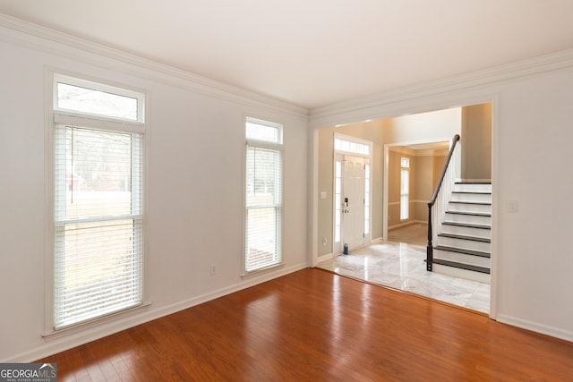 foyer entrance featuring stairway, crown molding, baseboards, and wood finished floors