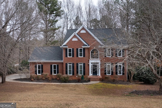 colonial-style house with brick siding and a front lawn