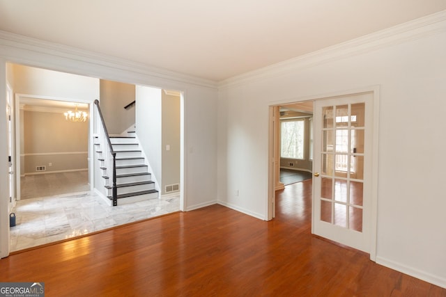 spare room with an inviting chandelier, crown molding, stairway, and wood finished floors