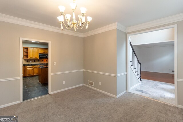 empty room featuring an inviting chandelier, ornamental molding, and carpet flooring