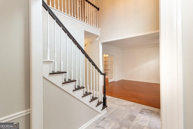 foyer with baseboards, stairway, ornamental molding, a towering ceiling, and wood finished floors