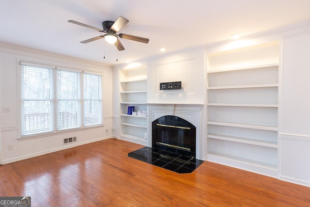 unfurnished living room with visible vents, a tile fireplace, baseboards, and hardwood / wood-style floors