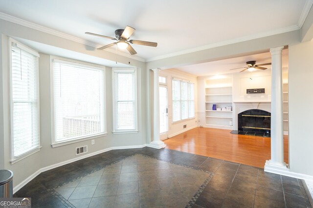 unfurnished living room with plenty of natural light, ornamental molding, ceiling fan, and ornate columns