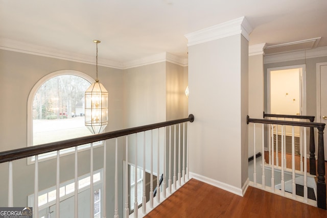 corridor featuring wood finished floors, baseboards, attic access, ornamental molding, and an upstairs landing