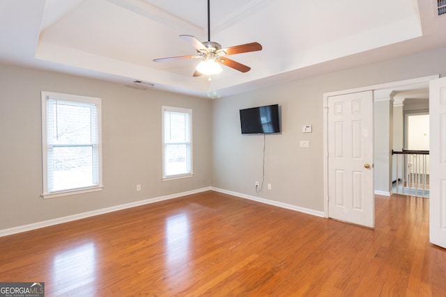 unfurnished bedroom featuring visible vents, a raised ceiling, baseboards, and light wood-style flooring