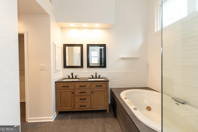 bathroom featuring double vanity, a jetted tub, ornamental molding, and a sink