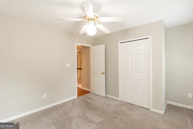 unfurnished bedroom featuring light colored carpet, ceiling fan, and a closet