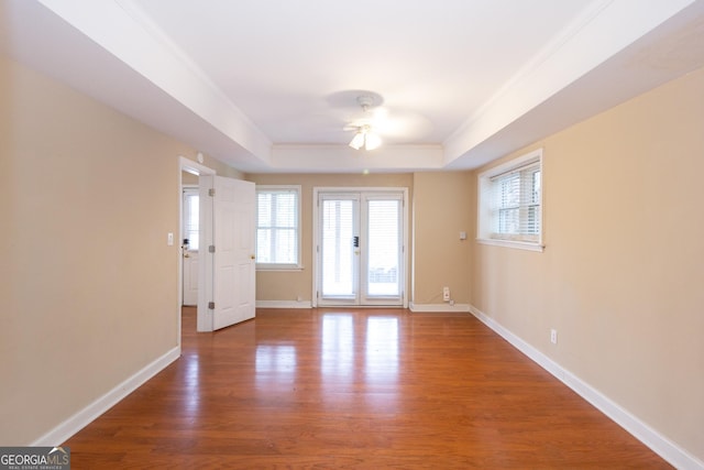 unfurnished room with baseboards, a raised ceiling, wood finished floors, and a ceiling fan