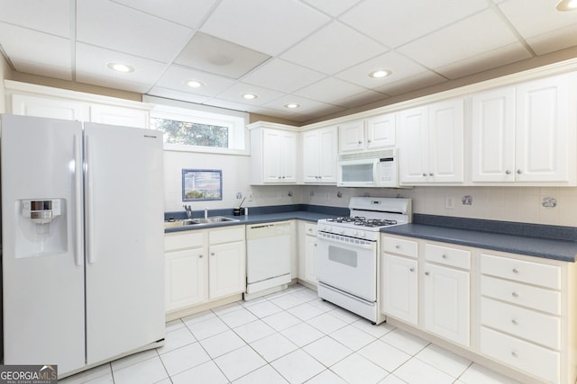 kitchen featuring a sink, dark countertops, white cabinetry, white appliances, and decorative backsplash