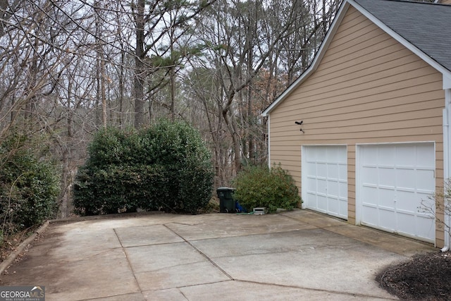 view of property exterior featuring a garage and a shingled roof