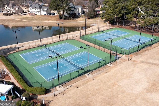 view of sport court with a water view and fence