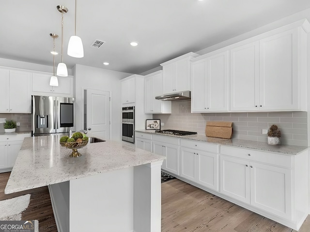 kitchen featuring white cabinetry, hanging light fixtures, light wood-type flooring, an island with sink, and stainless steel appliances