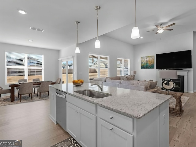 kitchen featuring sink, dishwasher, white cabinetry, a kitchen island with sink, and light stone countertops