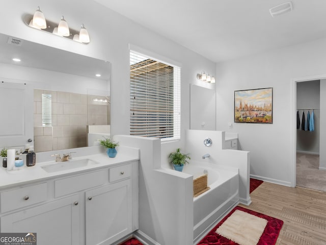 bathroom with a washtub, vanity, and hardwood / wood-style floors