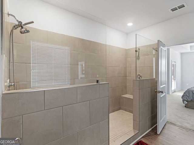 bathroom featuring a tile shower and hardwood / wood-style floors