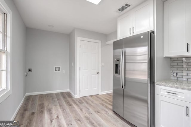 kitchen featuring light stone counters, light hardwood / wood-style flooring, white cabinets, and stainless steel refrigerator with ice dispenser