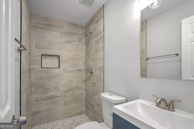 bathroom featuring vanity, toilet, and tiled shower