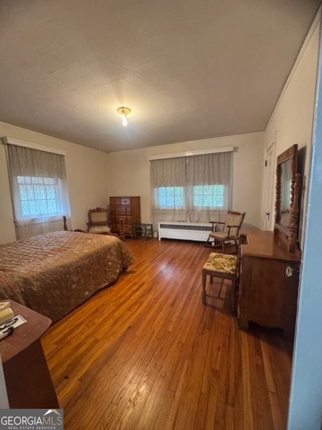 bedroom with a baseboard radiator and hardwood / wood-style floors