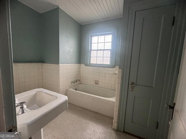 bathroom with tile patterned floors, a bathing tub, and tile walls