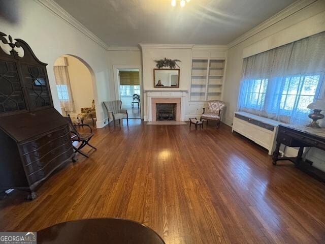 sitting room with ornamental molding, built in features, and dark hardwood / wood-style flooring