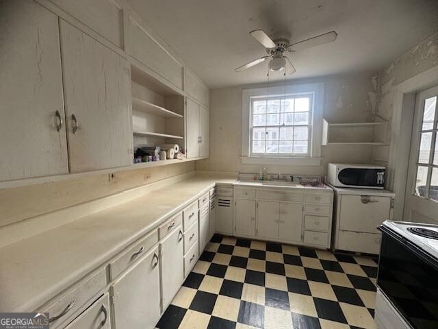 kitchen with ceiling fan, electric range, sink, and white cabinets