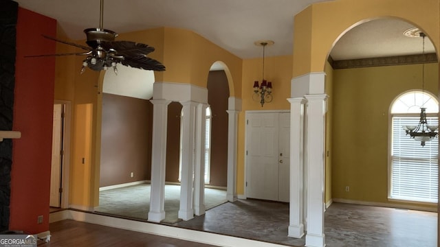 entrance foyer featuring dark hardwood / wood-style flooring, a towering ceiling, a wealth of natural light, and decorative columns