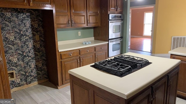 kitchen with black gas stovetop, double oven, and a kitchen island