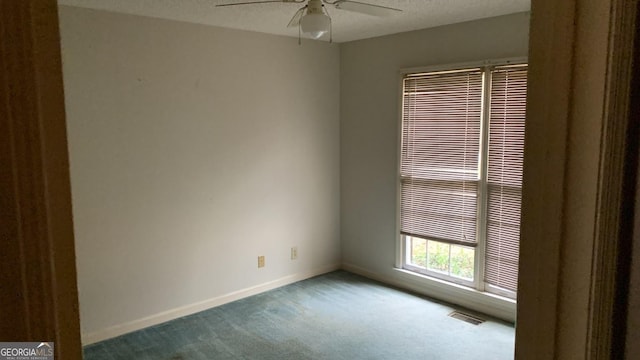 spare room featuring ceiling fan, a textured ceiling, and dark colored carpet